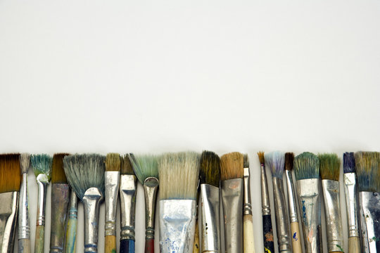 Well used artists paintbrushes on a white paper background