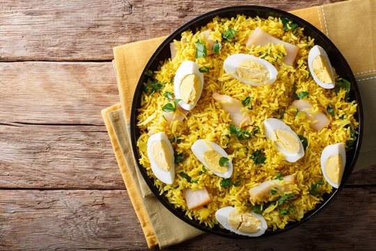 Tasty homemade Kedgeree with fish, boiled eggs, cilantro close-up on a plate. horizontal top view