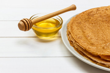 Homemade pancakes with honey on white plate, dipper, wooden table. top view. copy space