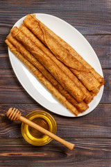 A pile of pancakes, honey, for the celebration of the carnival. Thin pancakes for breakfast. Pancakes and honey Maslenitsa. Pancakes with honey on a white wooden background. space for text