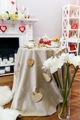 A St. Valentines Day decorated table, flowers and red detailed room.