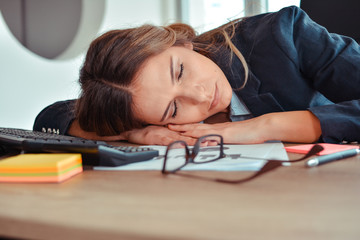 Overworked and tired young woman sleeping on desk