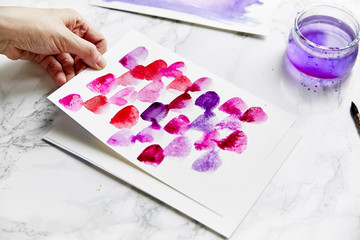 Close up shot with female hands painting with pink and crimson watercolor. Artist workplace concept, close up, white background.