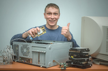 Happy computer technician engineer is holding in hands a new computer video card for replacement...