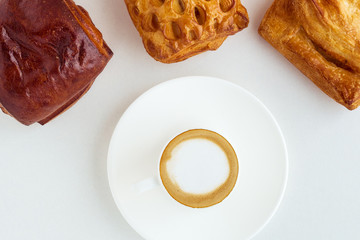 a cup of coffee and three buns on a white background.