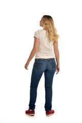 full length portrait of blonde lady wearing simple white shirt and jeans, standing pose isolated on white studio background.