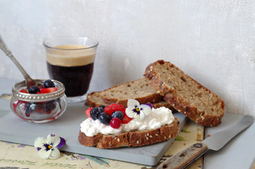 Vollkornbrot mit körnigem Frischkäse, Sommerbeeren-Salat und Hornveilchen