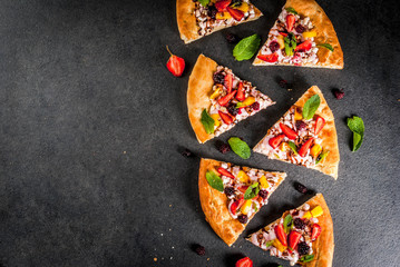 Summer snacks. Food for party. Fruit pizza with cream, currants, yogurt, strawberries, mango, peaches, bananas, blackberries, chocolate, walnuts, mint. On black table. Copy space top view