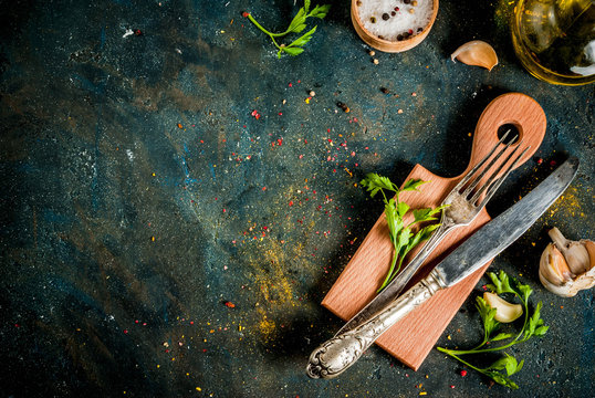 Cooking foor concept, spices, herb and oil for preparing dinner, with cutting board, table knife and fork, copy space top view