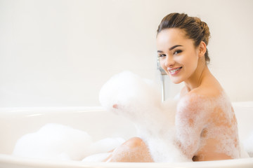smiling beautiful young woman taking bath at home