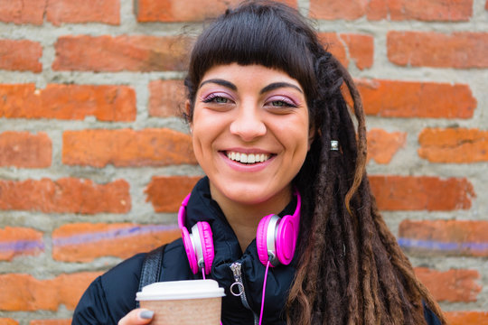 Urban Young Woman with Dreadlocks and Pink Headphones Smiling at Camera