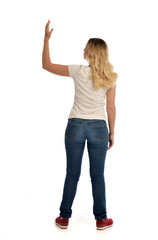 full length portrait of blonde lady wearing simple white shirt and jeans, standing pose isolated on white studio background.