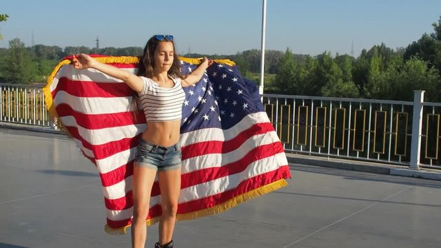 A beautiful girl is spinning on rollers with an American flag.