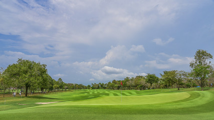Fototapeta na wymiar The green grass on golf course with blue cloud sky background
