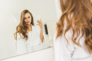beautiful woman taking selfie on smartphone in bathroom at home