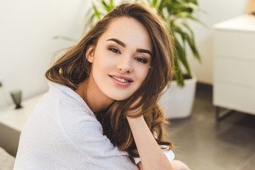 portrait of smiling pretty woman in bathrobe at home