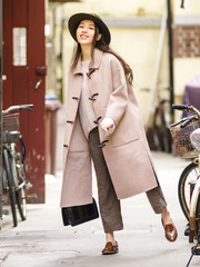 Beautiful young brunette woman wearing a beige coat in autumn city. Outdoor fashion portrait of...