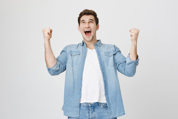 Cheerful dark-haired attractive European unshaven male with opened mouth being excited and glad to...
