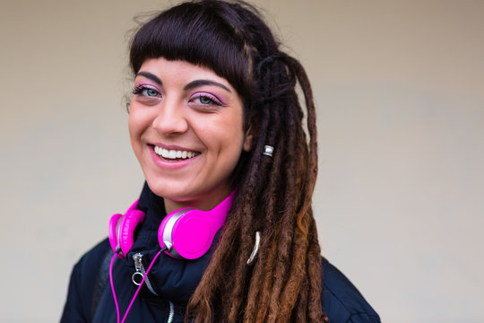 Urban Young Woman with Dreadlocks and Pink Headphones Smiling at Camera