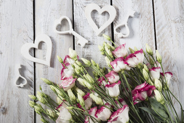 Holidays background : on white background pink with white flowers and wooden hearts and keys . Wedding, Valentines day, birthday or celebration background