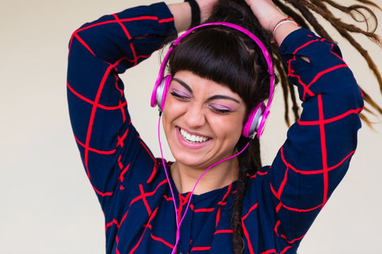 Urban Young Woman with Dreadlocks Listen to Music with Pink Headphones