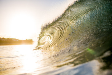 Dramatic lens flare with breaking wave at sunset on beach
