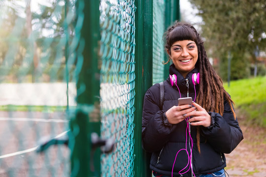 Urban Young Woman with Dreadlocks using a Mobile Phone Outdoors