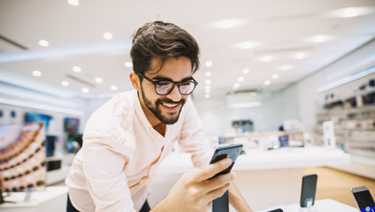 Close up of handsome young man buying new mobile in the electronic shop.