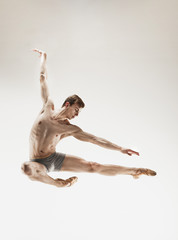 The male athletic ballet dancer performing dance isolated on white background.