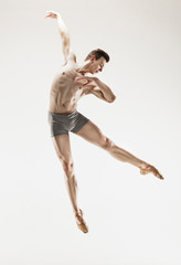 The male athletic ballet dancer performing dance isolated on white background.