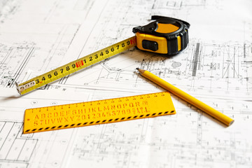 yellow ruler, yellow pencil and a collapsible ruler on architecture blueprint plan