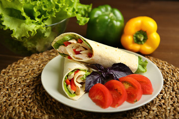 Shaurma without sauce with chicken, pepper, lettuce. Low-calorie roll from pita bread, next to purple basil and slices of tomatoes. Without roasting, raw. In the background pepper and lettuce leaves