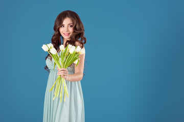 attractive girl showing bouquet of tulips isolated on blue