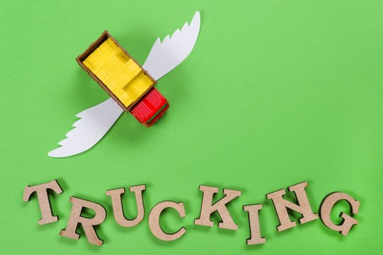 Abstract picture of a truck with wings and a word of trucking. Green background
