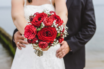 Braut hält Brautstrauß mit roten Rosen
