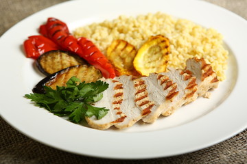 Grilled chicken with slices, with vegetables, bulgur on a white plate, decorated with parsley. Low-calorie, dietary food for a healthy lifestyle. Close up
