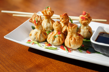 Portion of six fried wontons on a plate with sticks