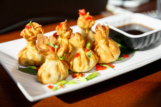 Portion of six fried wontons on a plate with sticks