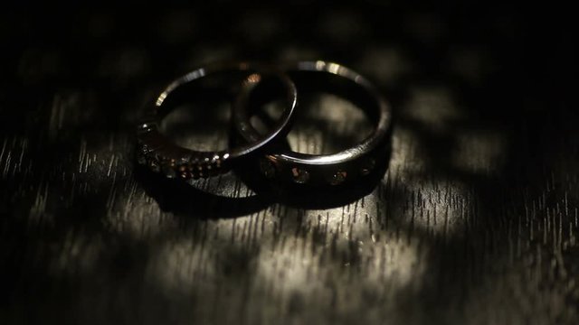 Two wedding rings on a kraft box. Dark scene
