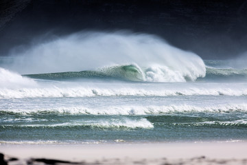 breaking wave with moody cliff face background in Cape Town, Atlantic Ocean