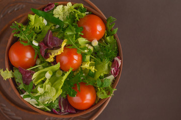 Healthy diet - salad with arugula, iceberg, cherry tomatoes, cabbage in clay dish close up