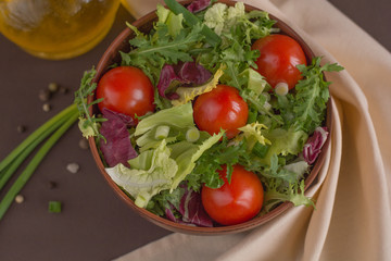 Cherry tomatoes salad with arugula, iceberg, cabbage near spices and napkin close up 