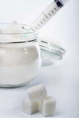 the syringe in a glass jar with sugar on light background