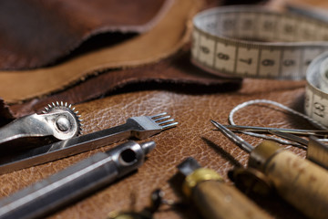 Furniture assembly parts and tools on a cow leather samples in the in the craftman's workshop....