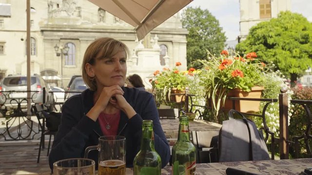 Woman sitting in an open air caffee looking to side watching around