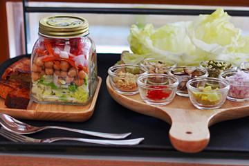 Salad in a Jar is layered with greens, with shredded carrots, chickpea, onion and tomato