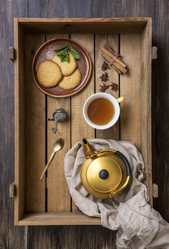 Overhead view of cup of green tea with mint, cookies and spices