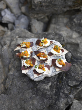 Dried reindeer meat on flatbread serven on a stone slab