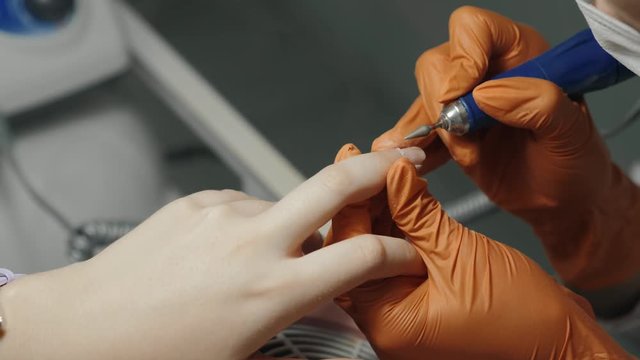 Manicure master during work. Close up hands with a nail file gloves on doctor