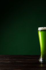 glass of green beer on wooden table, st patricks day concept
